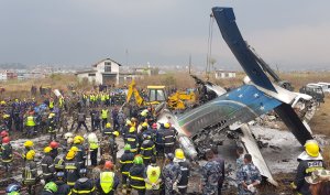 Nepali rescue workers gather around the debris of an airplane that crashed near the international airport in Kathmandu on March 12, 2018. (Credit: PRAKASH MATHEMA/AFP/Getty Images)