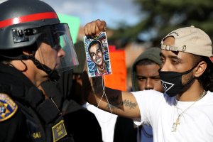 A Black Lives Matter protester holds a photo of Stephon Clark in front of a California Highway Patrol officer as they block an entrance to the 5 Freeway in Sacramento during a demonstration on March 23, 2018. (Credit: Justin Sullivan / Getty Images)