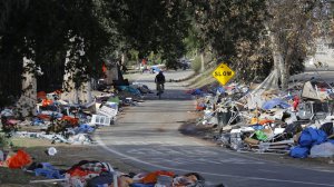A cyclist passes trash from the Santa Ana River homeless camp in Anaheim in February after it was cleared and more than 700 people relocated. (Credit: Allen J. Schaben / Los Angeles Times)