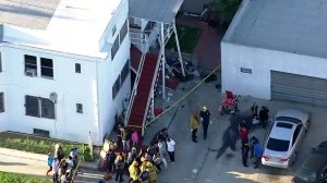 Investigators look through the scene where a car crashed into a home in South L.A., injuring six people, on March 23, 2018. (Credit: KTLA)