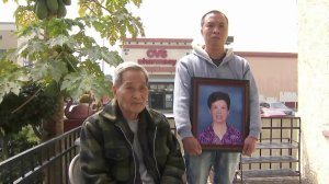 Bi Xu Chen's son hold a photo of the hit-and-run victim while her husband watches on on April 5, 2018. (Credit: KTLA)