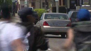 A gold Toyota Avalon flees after striking a pedestrian in South L.A. at a vigil for a cyclist on April 11, 2018. (Credit: KTLA)