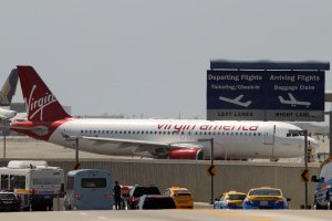 A Virgin America jet taxis into take-off position as cars enter the Los Angles International Airport on April 22, 2013. (Credit: David McNew/Getty Images)