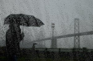 A pedestrian carries an umbrella while walking near the Bay Bridge on February 6, 2014 in San Francisco. (Credit: Justin Sullivan/Getty Images)