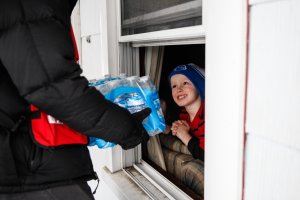 Jake McSigue, 6, of Linden, receives a package of bottled water through the window of his grandma's home in Flint, Michigan, on Jan. 21, 2016. (Credit: Sarah Rice / Getty Images)