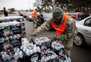 Army National Guard Specialist David Brown loads bottled water into waiting cars at a fire station on Jan. 21, 2016 in Flint, Michigan. (Credit: Sarah Rice / Getty Images)