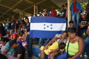 A man holds a Honduran national flag as Central Americans -taking part in a caravan called 'Migrant Viacrucis'- rest in Matias Romero, Oaxaca state, Mexico on April 2, 2018. (Credit: VICTORIA RAZO/AFP/Getty Images)