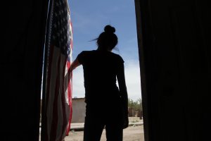 A U.S. flag hangs from the door of the house of a Mexican woman who looks toward the border line between Mexico and the United States in Ciudad Juarez, Mexico, on April 6, 2018. (Credit: Herika Martinez / AFP / Getty Images)