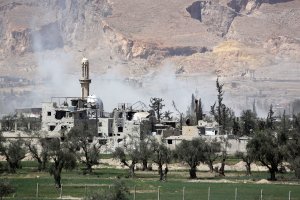 A picture taken on April 8, 2018, shows smoke billowing as Syrian Army soldiers advance in agricultural land on the eastern outskirts of Douma. (Credit: Stringer / AFP / Getty Images)