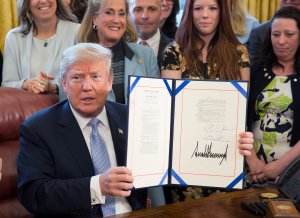 Donald Trump displays H.R. 1865, the "Allow States and Victims to Fight Online Sex Trafficking Act of 2017" after signing it into law at the White House on April 11, 2018. (Credit: Chris Kleponis-Pool/Getty Images)