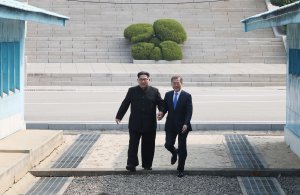 North Korea's leader Kim Jong Un, left, steps with South Korea's President Moon Jae-in across the Military Demarcation Line that divides their countries ahead of their meeting at Panmunjom on April 27, 2018. (Credit: Korea Summit Press Pool / AFP / Getty Images)