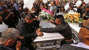 The brothers of Santos Hilario Garcia, who was killed in a crash while fleeing ICE in Kern County along with his partner, Marcelina Garcia Perfecto, are seen standing around the couple's caskets on the day of their funeral service at Our Lady of Guadalupe Church in Delano on April 2, 2018. (Credit: Al Seib / Los Angeles Times) 