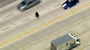 A driver runs across lanes of the 14 Freeway after abandoning a still-moving Stumptown Coffee truck at the end of a pursuit in Santa Clarita on April 2, 2018. (Credit: KTLA)
