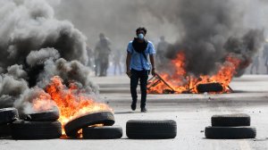 A masked protester walks between burning barricades April 20, 2018, in Managua, Nicaragua. (Credit: Alfredo Zuniga/AP)