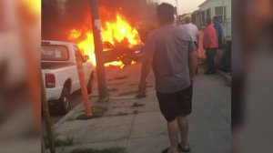 Bystanders watch a vehicle in flames following a crash in South L.A. on April 28, 2018.(Credit: Nora Castillo)