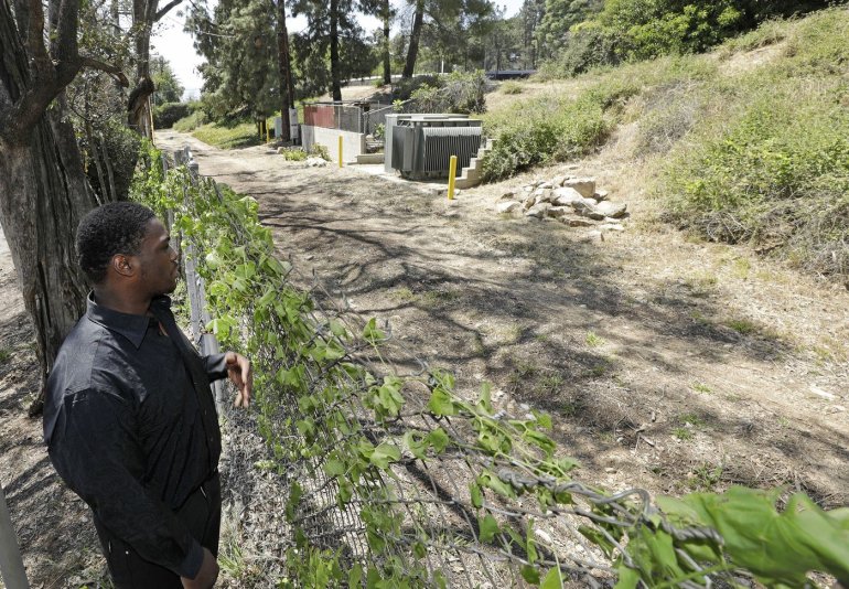 Matthew Whitaker looks at the spot (to the right of the pile of rocks) where he was abandoned as a newborn in brush near a trail in Altadena 20 years ago. (Credit: Myung J. Chun / Los Angeles Times)