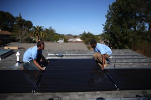 SolarCraft workers Craig Powell (left) and Edwin Neal install solar panels on the roof of a home in San Rafael, California on February 26, 2015. (Credit: Justin Sullivan/Getty Images)