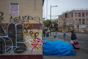 Homeless people camp on a sidewalk on Skid Row near an old sign prohibiting them from being on the sidewalk on May 1, 2017 in Los Angeles. (Credit: David McNew/Getty Images)