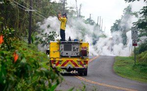 A firefighter takes photos near steam rising from a fissure in Leilani Estates subdivision on Hawaii's Big Island on May 4, 2018. (Credit: FREDERIC J. BROWN/AFP/Getty Images)