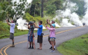 People take photos of lava as steam rises from a fissure in Leilani Estates subdivision on Hawaii's Big Island on May 4, 2018. (Credit: FREDERIC J. BROWN/AFP/Getty Images)