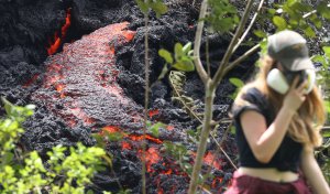 Lava flows at a new fissure in the aftermath of eruptions from the Kilauea volcano on Hawaii's Big Island as a local resident walks nearby after taking photos on May 12, 2018 in Pahoa, Hawaii. (Credit: Mario Tama/Getty Images)