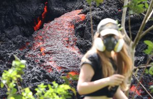 Lava flows at a new fissure in the aftermath of eruptions from the Kilauea volcano on Hawaii's Big Island as a local resident walks nearby after taking photos on May 12, 2018 in Pahoa, Hawaii. (Credit: Mario Tama/Getty Images)