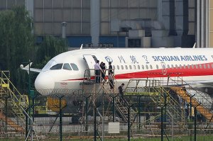 This photo taken on May 14, 2018 shows employees checking a Sichuan Airlines Airbus A319 after an emergency landing, as a broken cockpit window (left) is covered, in Chengdu in China's northwestern Sichuan province. - The pilot who made an emergency landing in southwest China after a broken cockpit window sucked his co-pilot halfway out of the aircraft was hailed as a "hero" on May 15 by astonished citizens. All 128 people aboard the Airbus A319 of Sichuan Airlines survived the ordeal. (Credit: AFP/Getty Images)