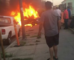 Bystanders watch a vehicle in engulfed flames following a suspected DUI crash in South Los Angeles on April 28, 2018.(Credit: Nora Castillo)