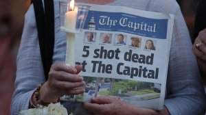 A woman holds an edition of the Capital newspaper during a candlelight vigil on June 29, 2018, to honor the five people who were shot and killed in Annapolis, Maryland. (Credit: Mark Wilson/Getty Images)