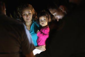 Central American asylum seekers, including a Honduran girl, 2, and her mother, are taken into custody near the U.S.-Mexico border on June 12, 2018, in McAllen, Texas. The group of women and children had rafted across the Rio Grande from Mexico and were detained by U.S. Border Patrol agents before being sent to a processing center for possible separation. (Credit: John Moore/Getty Images)