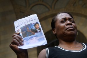 Carmen Ashley, the great aunt of Antwon Rose II, cries as she holds the memorial card from Rose's funeral during a protest calling for justice for the 17-year-old on June 26, 2018 in downtown Pittsburgh, Pennsylvania. (Credit: Justin Merriman/Getty Images)