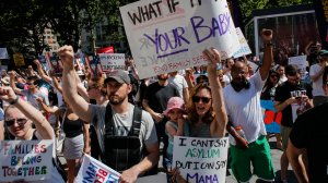 A family hold signs as they attend the nationwide “Keeping Families Together” march in New York City on June 30, 2018. in New York City. (Credit: Kena Betancur/Getty Images)