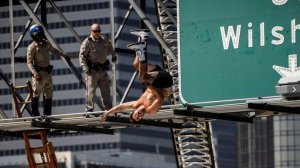 California Highway Patrol officers watch as a man who had scaled a freeway sign and shut down the southbound 110 Freeway does a backflip onto massive inflatable cushions set up below in downtown Los Angeles. (Credit: Marcus Yam / Los Angeles Times)