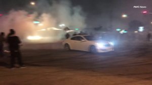 Spectators watch a vehicle perform doughnuts in a Pico Rivera intersection on July 23, 2018. (Credit: RMG News)
