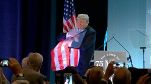 President Donald Trump hugs the American flag after speaking at a National Federation of Independent Business event in Washington on June 19, 2018. (Credit: CNN)