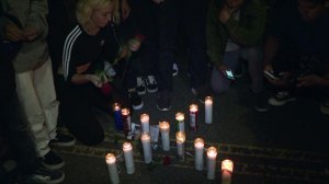 A fan lays roses next to memorial candles in the shape of an X during a vigil for rapper XXXTentacion on Melrose Avenue on June 19, 2018. (Credit: KTLA)