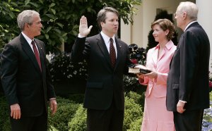 Brett Kavanaugh (second from left) is sworn in by Supreme Court Justice Anthony Kennedy (right) to be a judge at the U.S. Circuit Court of Appeals for the District of Columbia, as his wife Ashley and President George W. Bush look on during a swearing-in ceremony at the White House Rose Garden on June 1, 2006. (Credit: Alex Wong / Getty Images)