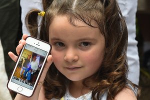 Luciana Villavicencio, the 4-year-old daughter of Pablo Villavicencio, holds up a photo of her family on a cellphone during a press conference in New York on June 18, 2018. (Credit: Timothy A. Clary / AFP / Getty Images)