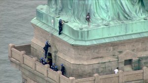 A woman climbed the base of the Statue of Liberty on July 4, 2018, and seven people were arrested on Liberty Island, all of whom are believed to be protesters, law enforcement sources told CNN. (Credit: WPIX via CNN)