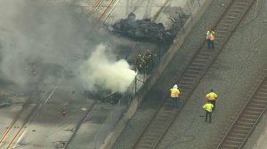 Authorities walk along Metro tracks as firefighters respond to a deadly tanker truck crash on the 105 Freeway in Hawthorne on Aug. 24, 2018. (Credit: KTLA)