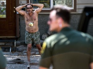 Sheriff deputies talk to Forrest Gordon Clark, a Holy Jim Canyon resident whose home was the only surviving structure in his 14 cabin area. (Credit: Mindy Schauer / Orange County Register via Getty Images)