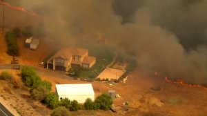 A brush fire inches closer to a home in San Diego County on Aug. 13, 2018. (Credit: KSWB)