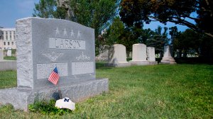 A flag is placed at the base of the tombstone of U.S. Navy Adm. Charles “Chuck” Larson at the U.S. Naval Academy in Annapolis, Maryland, on Aug. 24, 2018, near where Sen. John McCain will be laid to rest. (Credit: JIM WATSON/AFP/Getty Images)