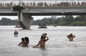 CIUDAD HIDALGO, MEXICO - OCTOBER 20: Immigrants struggle against the current of the Suchiate River while crossing the border from Guatemala into Mexico on October 20, 2018 at Ciudad Hidalgo, Mexico. Many others waited on a bridge to be allowed by Mexican authorities to cross. (Credit John Moore/Getty Images)