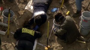 Investigators are seen examining a location at the property near Littlerock where the remains of three people were found. (Credit: KTLA)