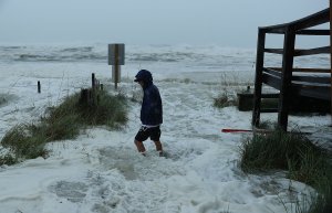 Cameron Sadowski walks along where waves are crashing onto the beach as the outer bands of hurricane Michael arrive on October 10, 2018 in Panama City Beach, Florida. (Credit: Joe Raedle/Getty Images)