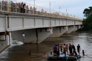 Honduran migrants heading in a caravan to the U.S. await for fellow migrants to jump from the Guatemala-Mexico international border bridge into the Suchiate river, to swim or board a raft to reach Mexico, in Ciudad Hidalgo, Chiapas state, on Oct. 19, 2018. (Credit: Pedro Pardo / AFP / Getty Images)