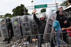 A Mexican riot policeman shields an immigrant mother and child from flying rocks during a clash between police and a migrant caravan on the border between Mexico and Guatemala on Oct. 19, 2018, in Ciudad Tecun Uman, Guatemala. (Credit: John Moore / Getty Images)