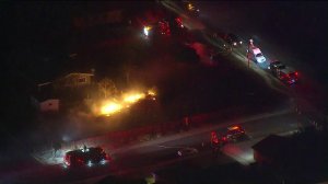 Firefighters work to extinguish flames from the Sierra Fire that spread to the yard of a Fontana residence on Nov. 13, 2018. (Credit: KTLA)