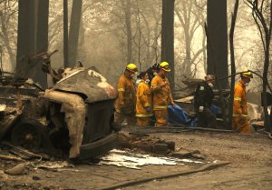 Firefighters carry a body bag with human remains that were discovered at a mobile home park that was destroyed by the Camp Fire on Nov. 14, 2018 in Paradise, California. (Credit: Justin Sullivan/Getty Images)